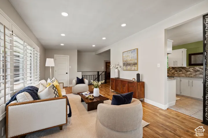 Living area with wood-finish flooring, recessed lighting, and expansive windows featuring plantation shutters