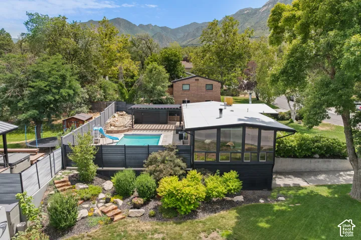 Exterior features a pool with surrounding deck, a slatted privacy fence, and tiered landscaping