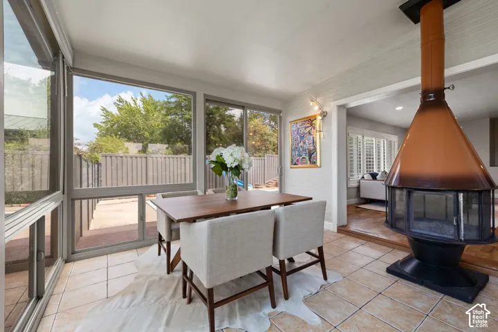 Sunroom featuring a freestanding fireplace, tile flooring, and expansive windows
