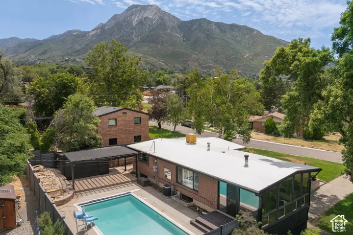 Residential property featuring a rectangular pool, covered patio area, and a dark brick exterior with a flat roofline