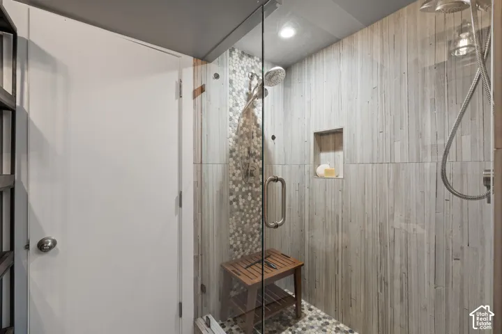 Glass-enclosed shower featuring wood-finish wall tiling, a built-in recessed niche, and mosaic pebble flooring