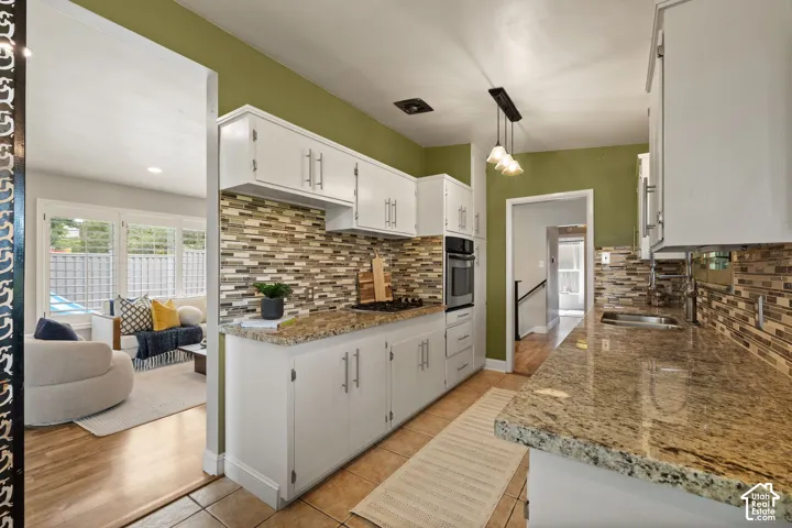 Kitchen featuring white cabinetry, stone countertops, and a full tile backsplash