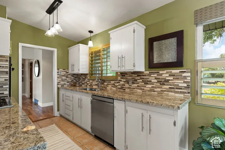 Kitchen featuring white cabinetry, granite countertops, a mosaic tile backsplash, and a stainless steel dishwasher