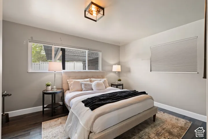 Bedroom featuring dark wood-finish flooring, light grey walls, and white baseboards