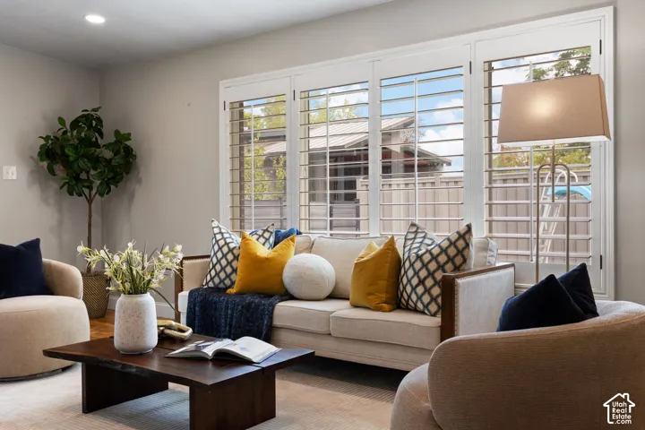 Living room featuring plantation shutters, recessed ceiling lighting, a wood-finish coffee table, light-toned walls, and carpet flooring