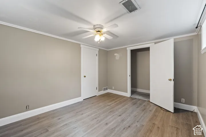 Spacious interior room featuring wood-finish flooring, neutral wall tones, and white trim