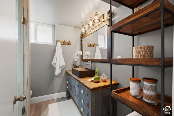 Bathroom featuring a rustic wood-finish vanity with a vessel sink, an industrial-style mirror, and a multi-light fixture