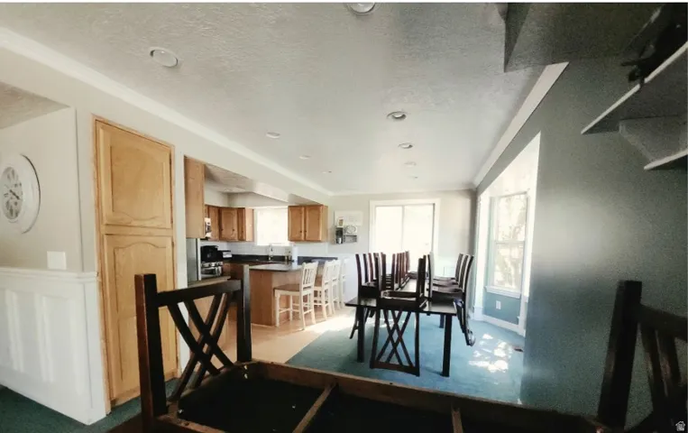 Open-concept living space featuring a kitchen with wood cabinetry, black countertops, and a peninsula with bar seating