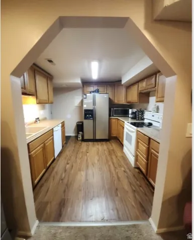 U-shaped kitchen with wood-finish flooring, light wood cabinetry, and neutral countertops
