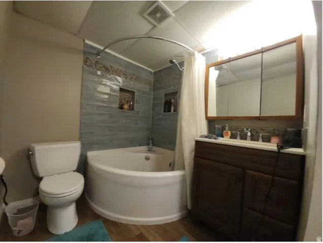 Bathroom featuring a corner soaking tub with light blue subway tile surround and decorative accent tile