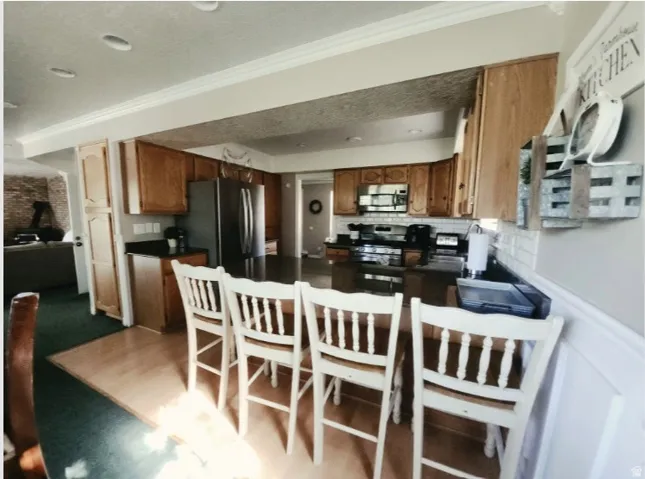 Kitchen featuring wood cabinetry, dark countertops, stainless steel appliances, and a subway tile backsplash