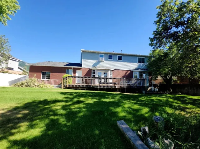 Spacious backyard with a large wood deck, featuring a brick and siding exterior