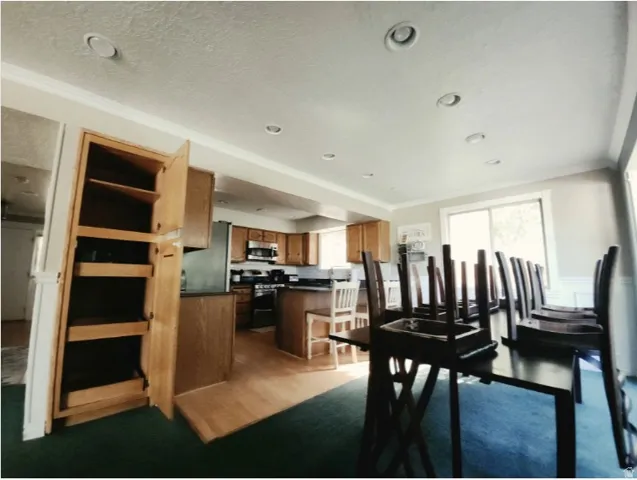 Open-concept kitchen and dining area featuring recessed lighting, a sliding glass door, wood-finish flooring, and built-in wood cabinetry