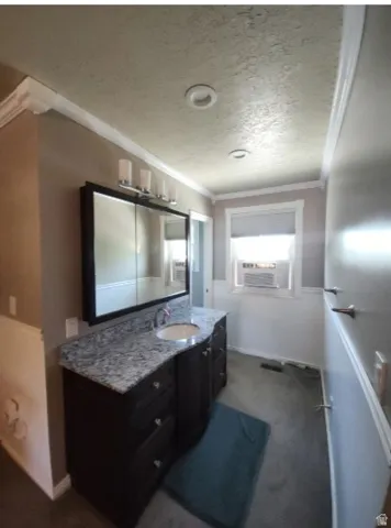 Vanity in walkway to 3/4 bath Primary Bedroom, featuring a dark wood vanity with an integrated sink, granite countertop, and wall-mounted faucet