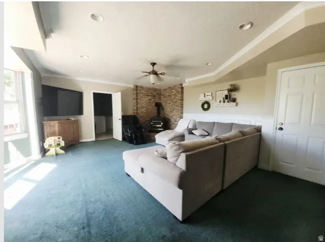 Spacious room featuring a corner brick-clad wall with a wood-burning stove, recessed lighting, and a ceiling fan