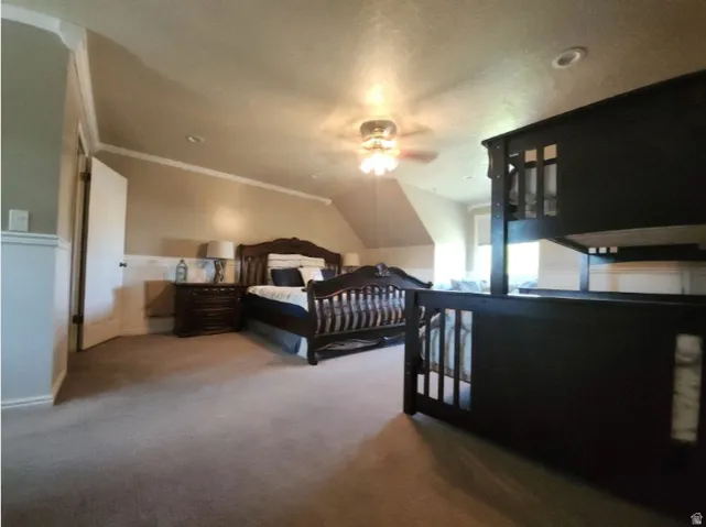 Spacious room featuring sloped ceilings, crown molding, and wainscoting