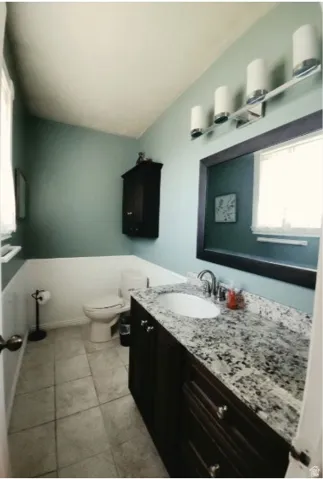 1/2 Bath for guests, featuring a dark wood-finish vanity with a light speckled countertop, an oval undermount sink, and a chrome faucet