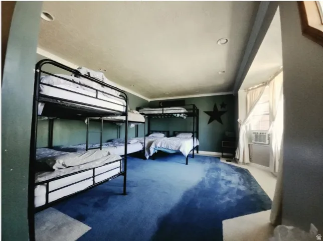 Spacious room featuring blue carpeting, recessed lighting, crown molding, and multiple bunk beds