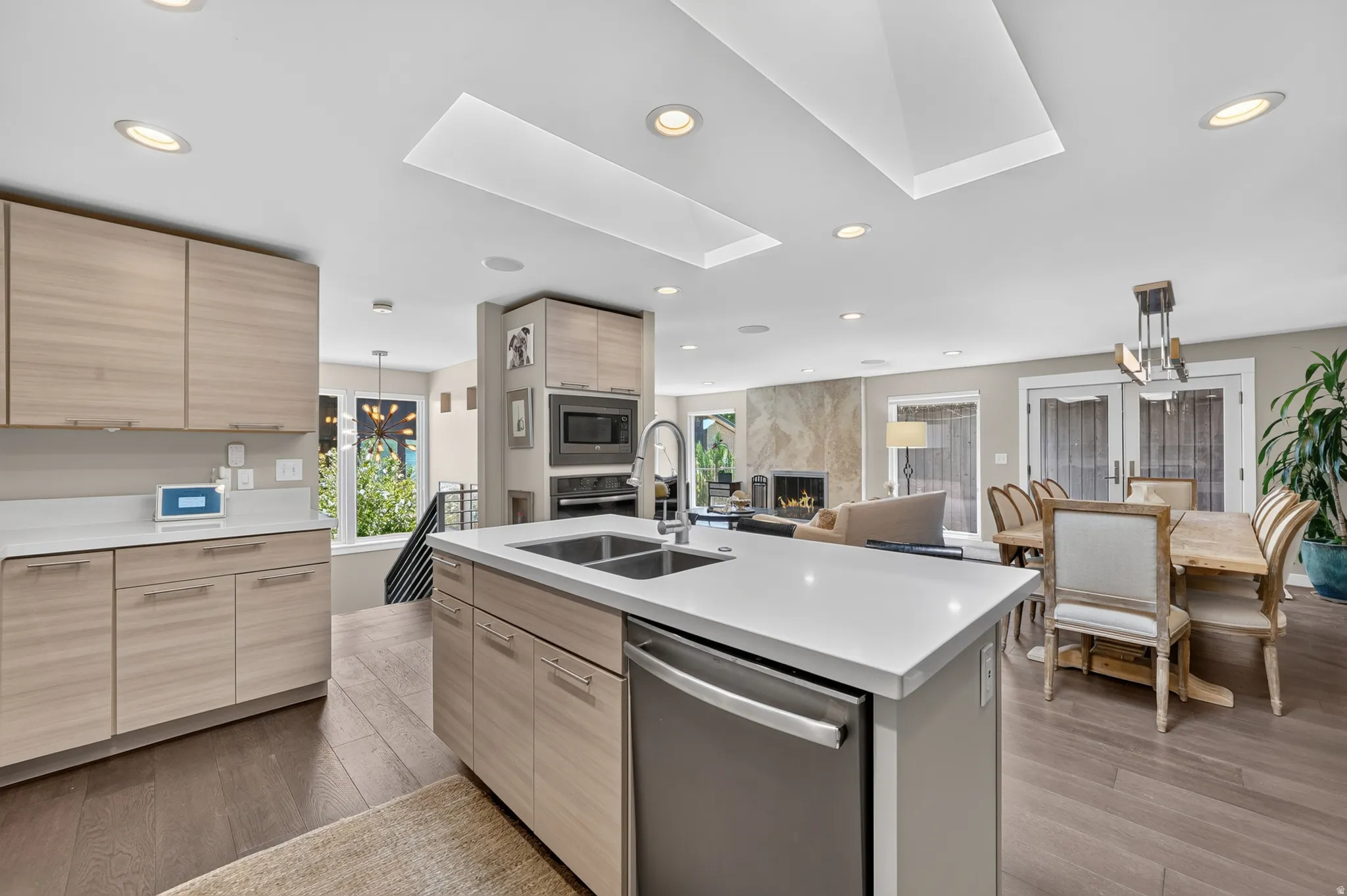 Kitchen island featuring a stainless steel sink, integrated dishwasher, and white countertop