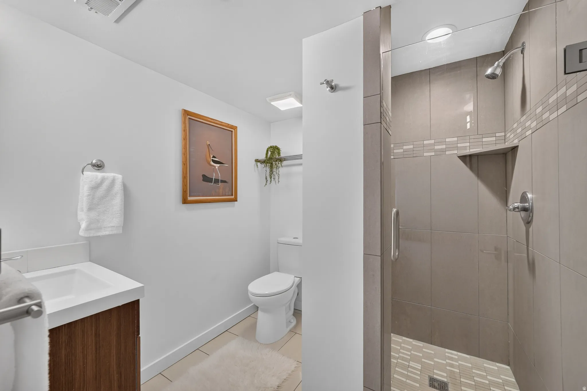 Full bathroom featuring a walk-in shower with glass enclosure, wall-mounted showerhead, and tiled walls with decorative accents