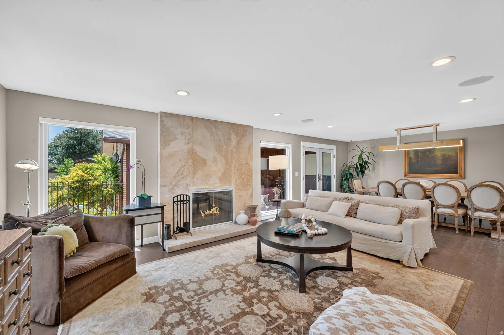 Spacious living area featuring a stone-clad fireplace with hearth, recessed lighting, and large windows