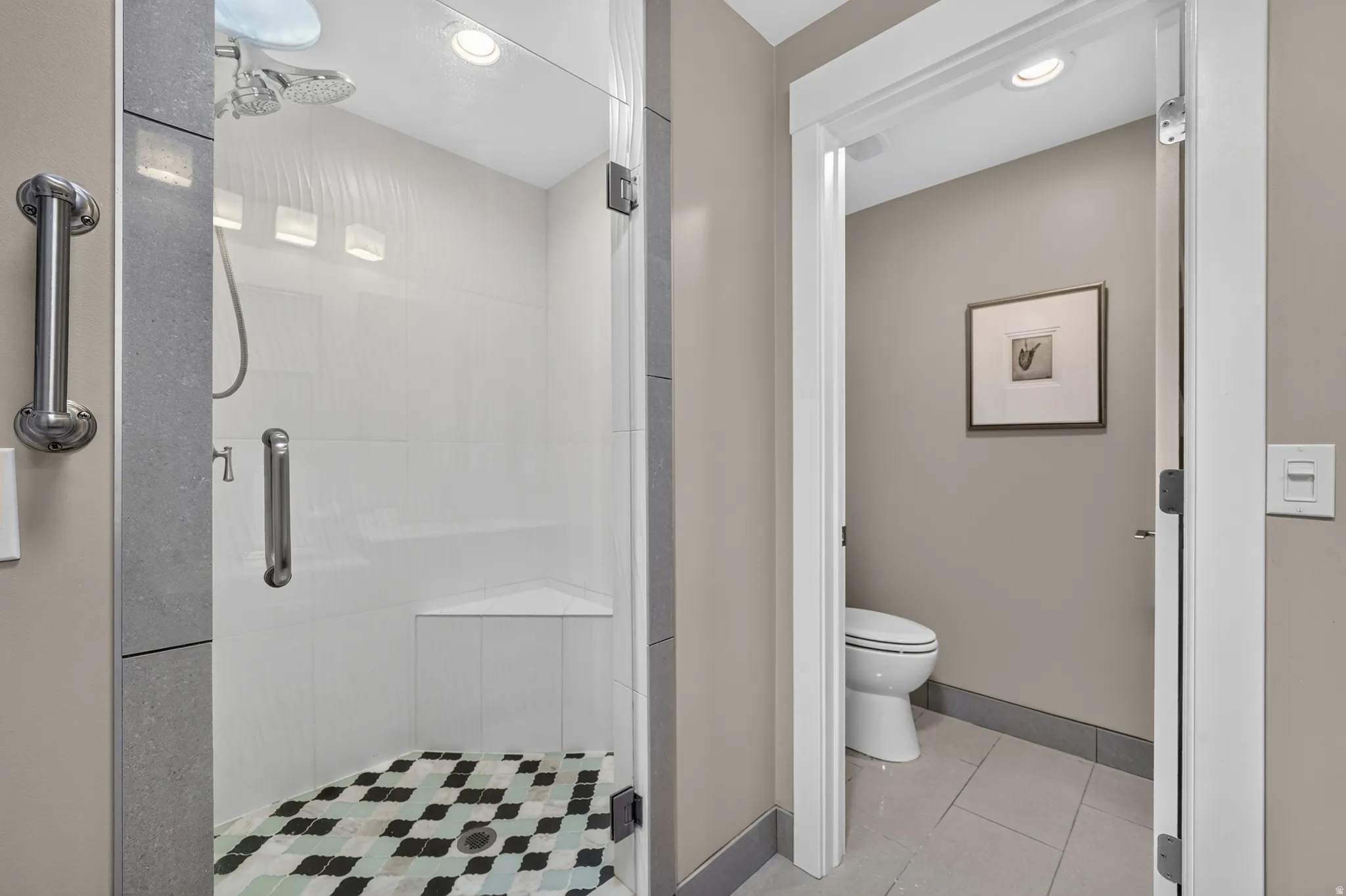 Glass-enclosed shower with a patterned mosaic tile floor and a built-in corner bench