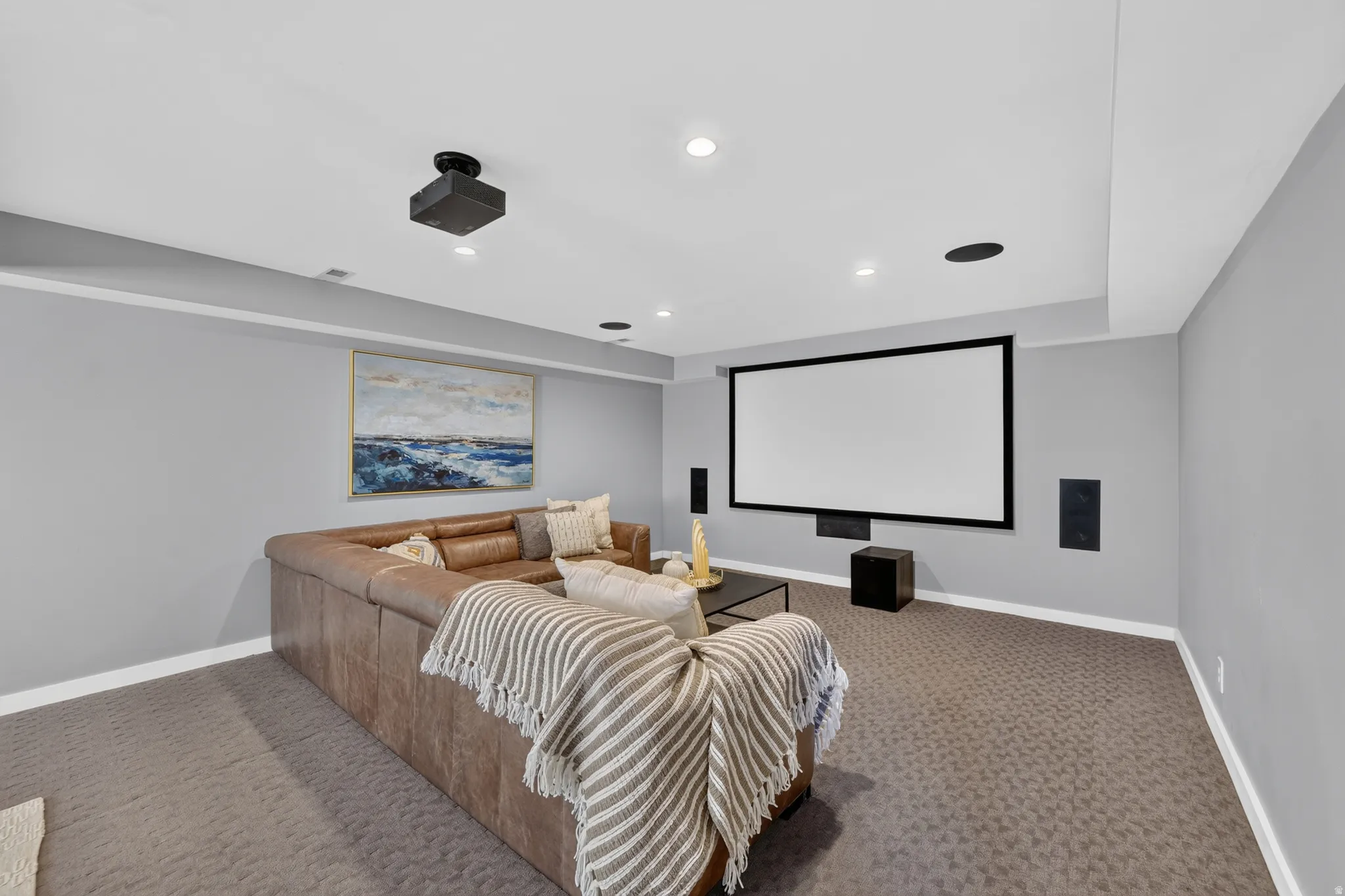 Dedicated media room featuring a large projection screen, built-in wall speakers, and a ceiling-mounted projector