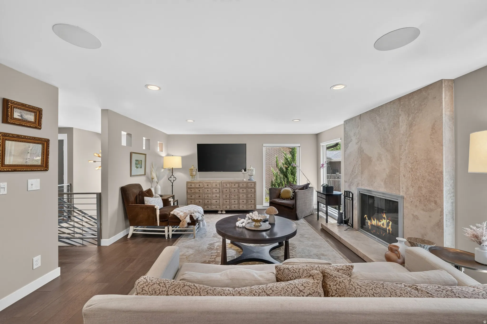 Spacious living area featuring dark wood-finish flooring, recessed lighting, and built-in ceiling speakers