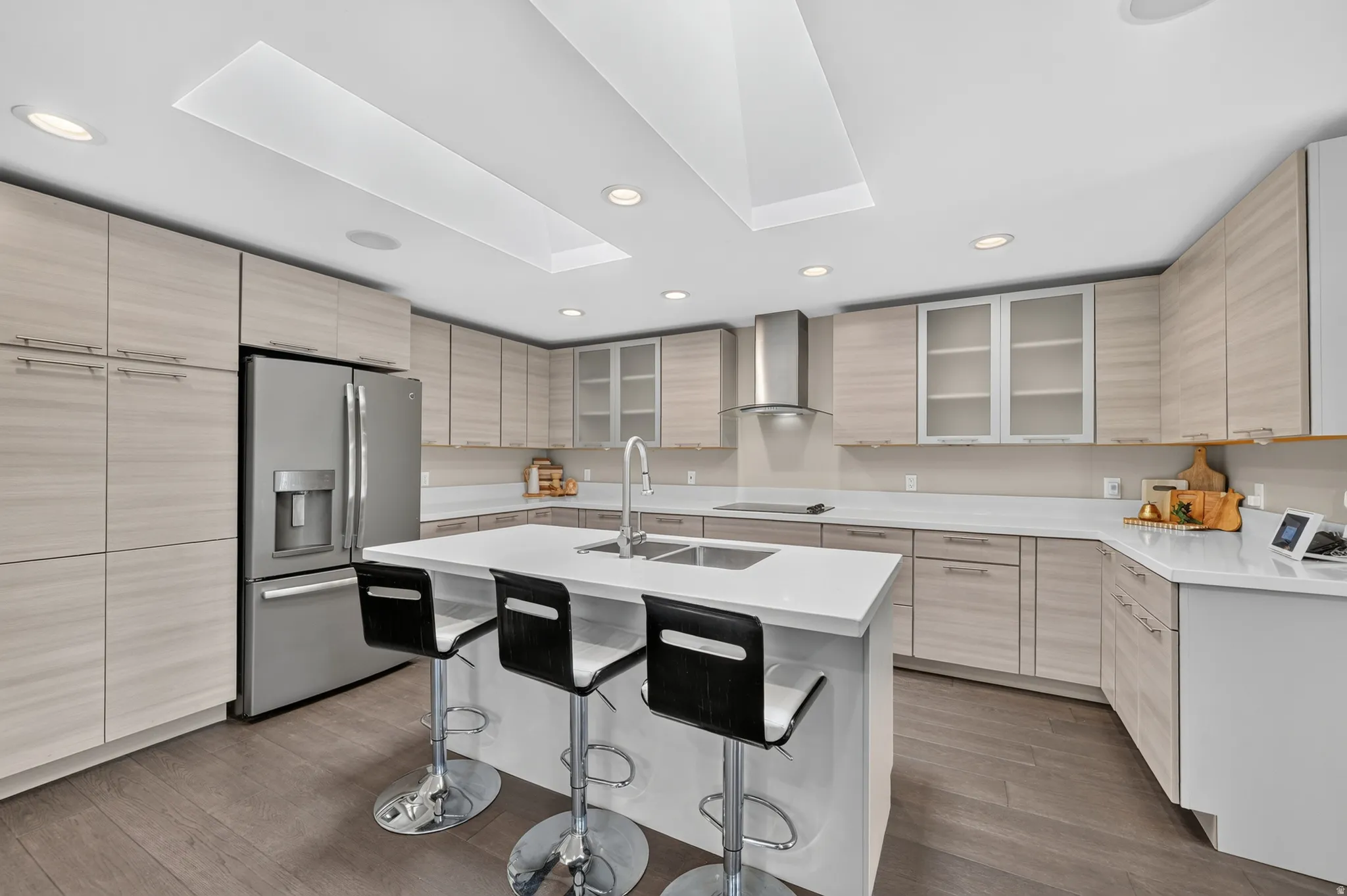 Modern kitchen featuring light wood-finish cabinetry, stainless steel appliances, and a central island with a sink and seating area