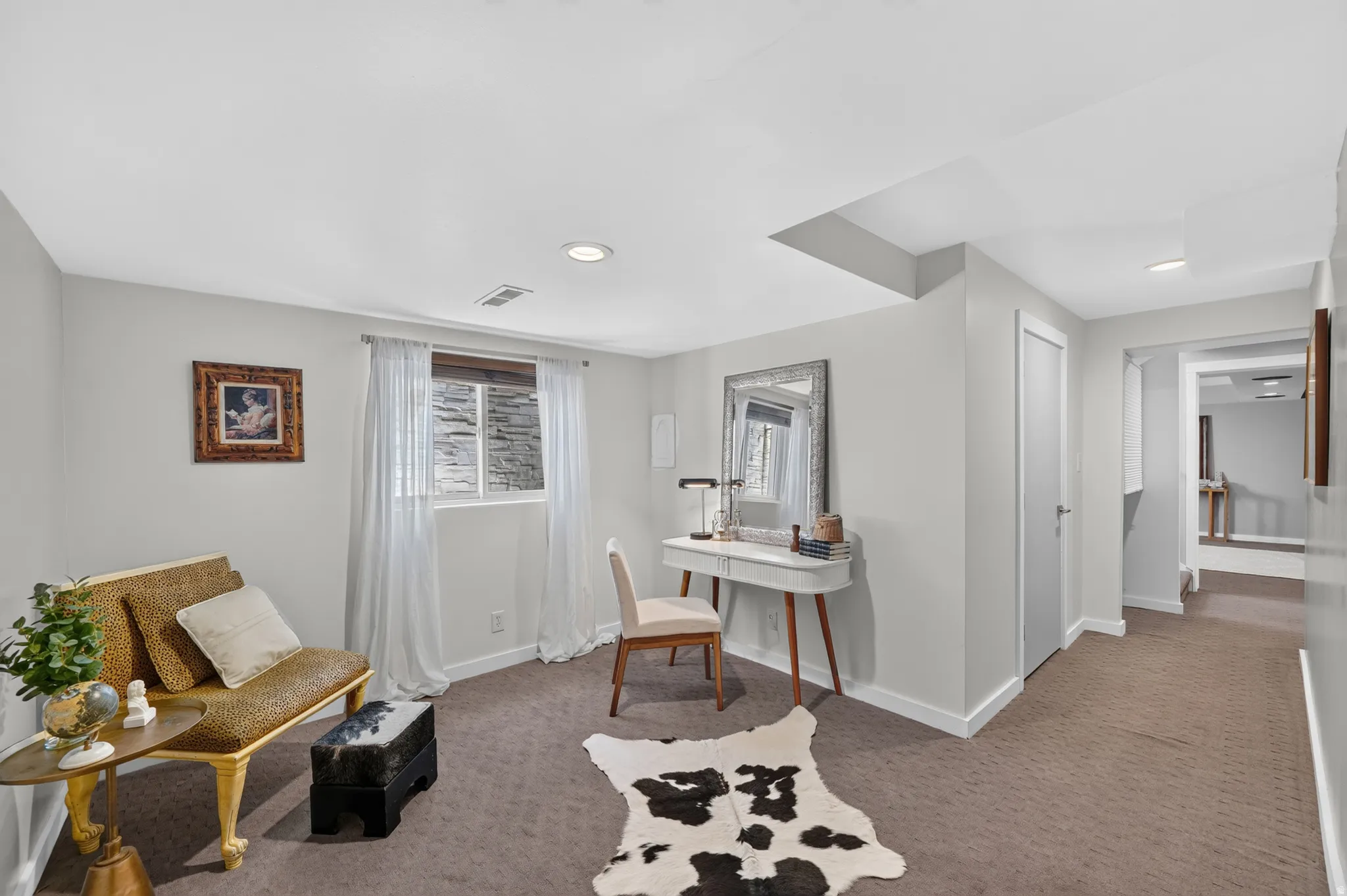 Carpeted room with recessed lighting and a window featuring white sheer curtains
