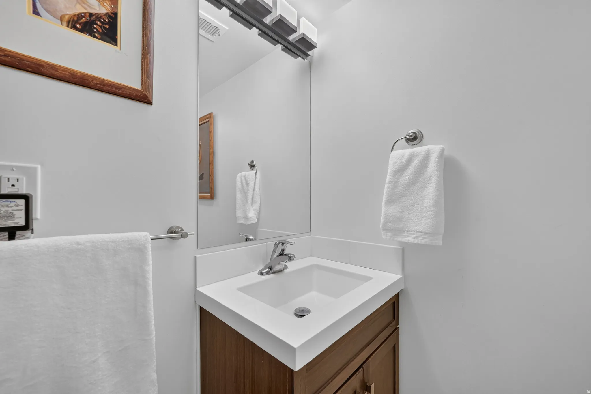 Modern vanity with a sleek white countertop, undermount sink, and wood-finish cabinetry