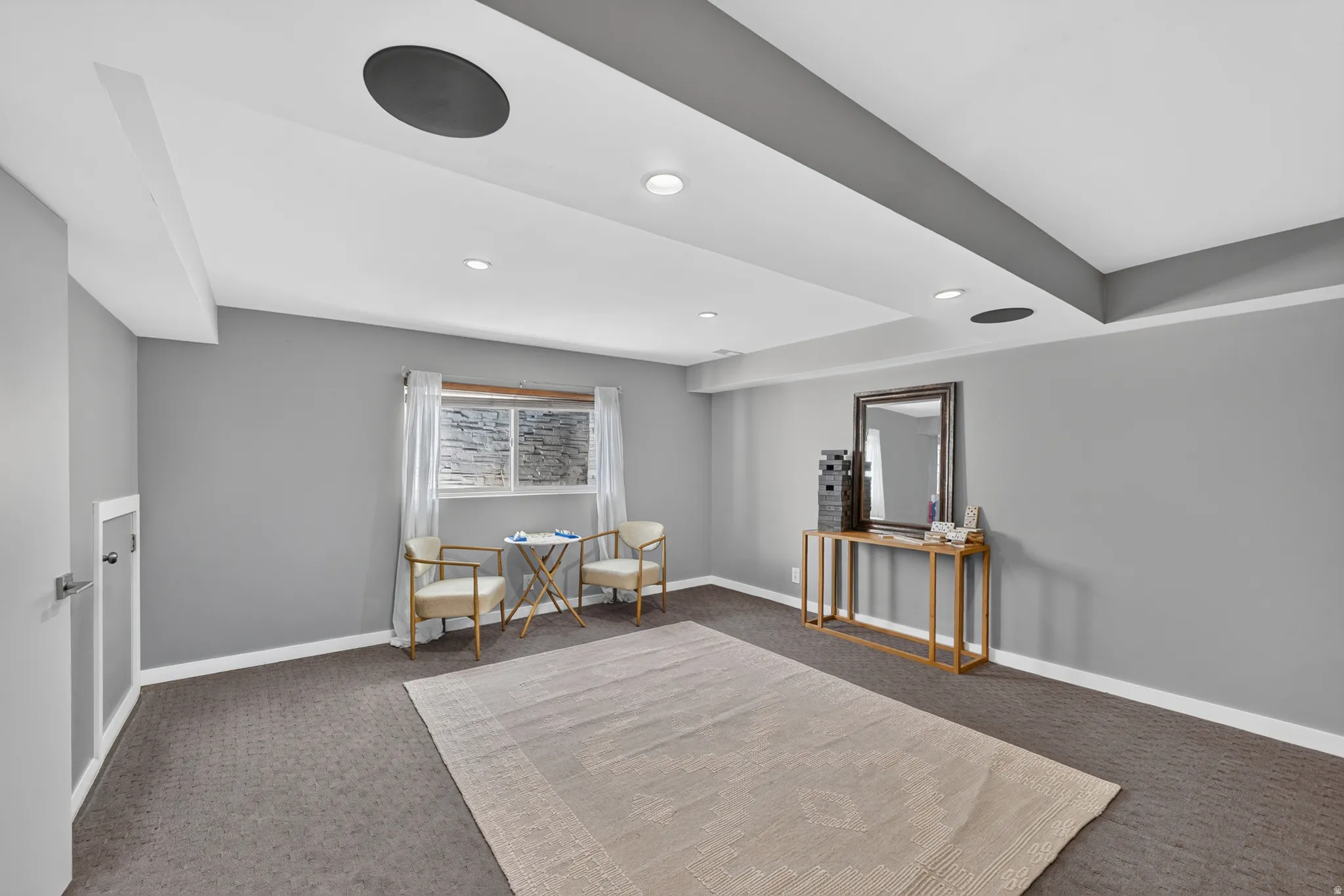 Recessed lighting illuminating a spacious room with gray walls and patterned carpeting