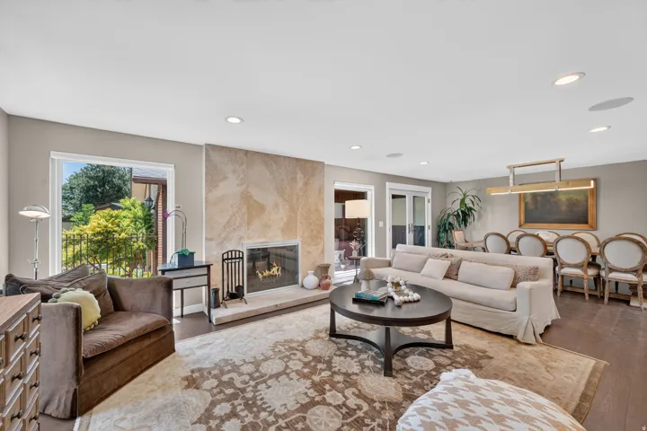 Spacious living area featuring a stone-clad fireplace with hearth, recessed lighting, and large windows