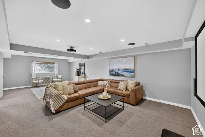 Spacious carpeted room featuring recessed lighting, a ceiling-mounted projector, and a large projection screen