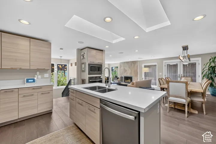 Kitchen island featuring a stainless steel sink, integrated dishwasher, and white countertop