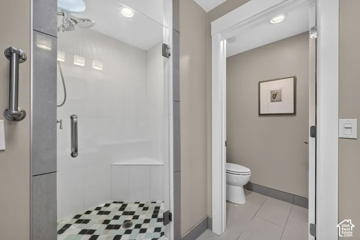 Glass-enclosed shower with a patterned mosaic tile floor and a built-in corner bench