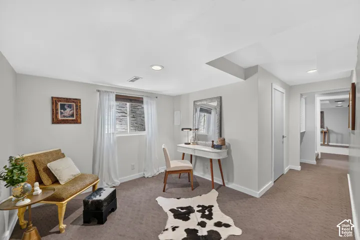 Carpeted room with recessed lighting and a window featuring white sheer curtains
