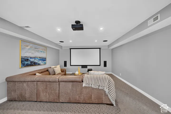 Dedicated media room featuring a large projection screen, recessed lighting, and wall-mounted speakers