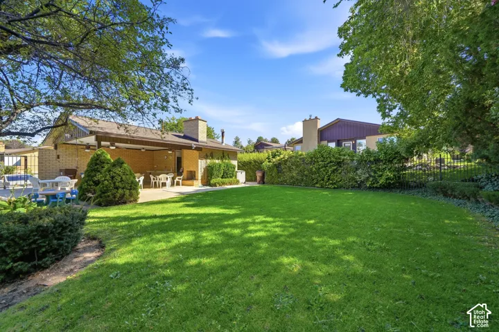 Expansive grassy yard with mature trees and a covered patio area