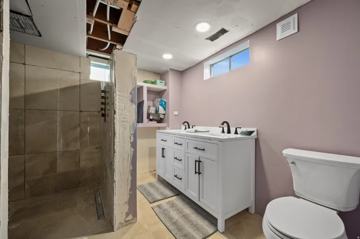 Bathroom featuring a double vanity with white cabinetry and dark hardware, dual undermount sinks, and dark-finish faucets