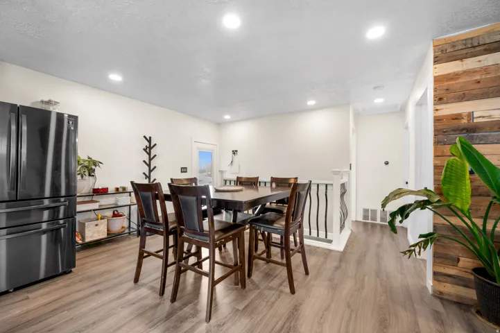 Open-concept dining area featuring wood-finish flooring, recessed lighting, and a modern wood accent wall