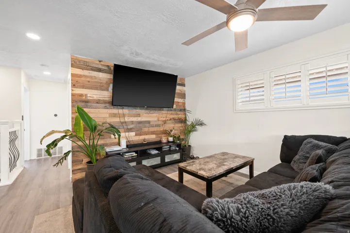 Living area showcasing a wood plank accent wall, recessed lighting, and wood-finish flooring