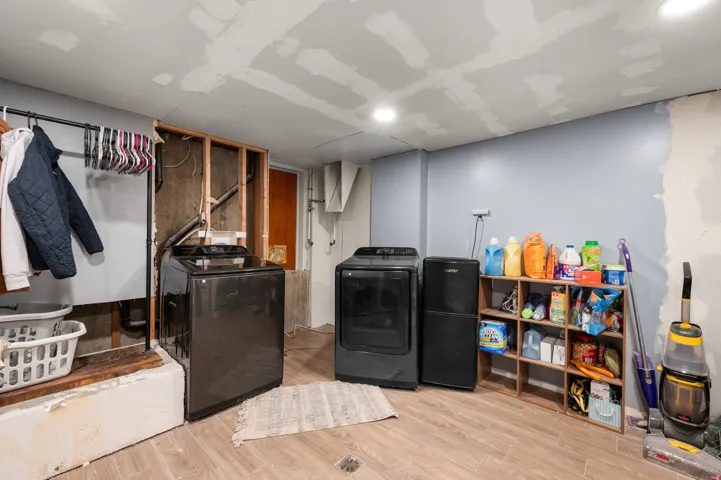 Laundry area featuring wood-finish flooring, recessed lighting, and a partially finished wall