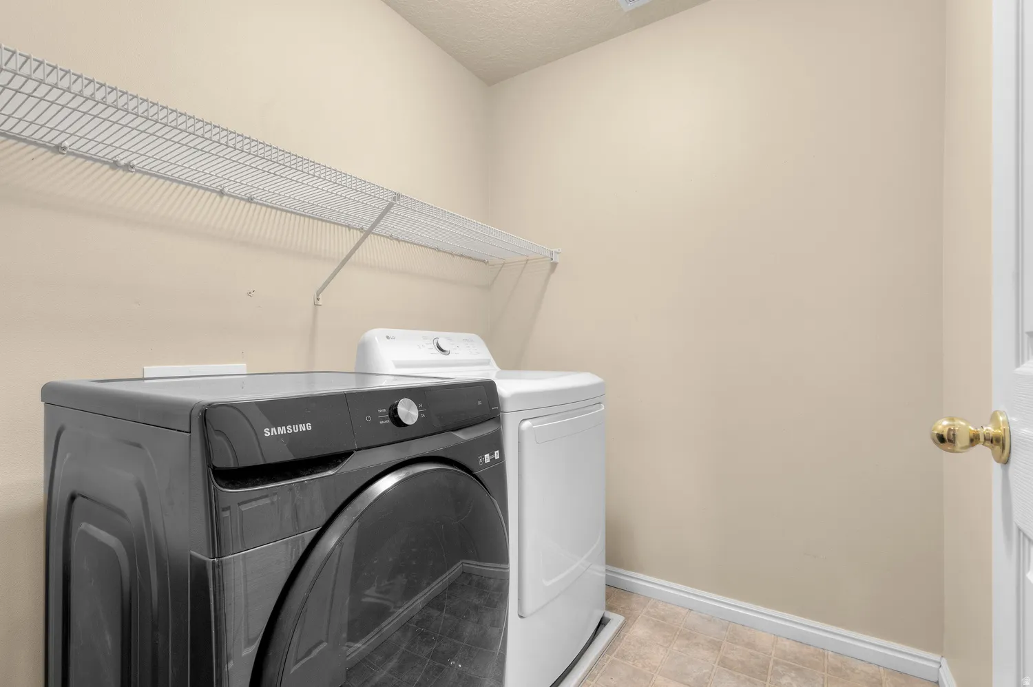 Dedicated laundry area featuring wire shelving, neutral wall paint, and resilient flooring