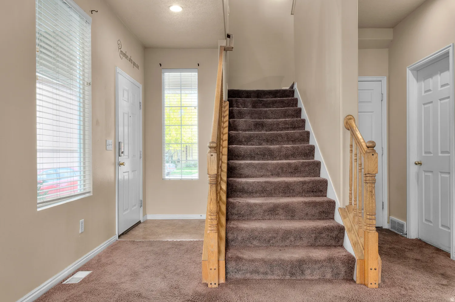 Entryway featuring carpeted flooring and a wood baluster staircase