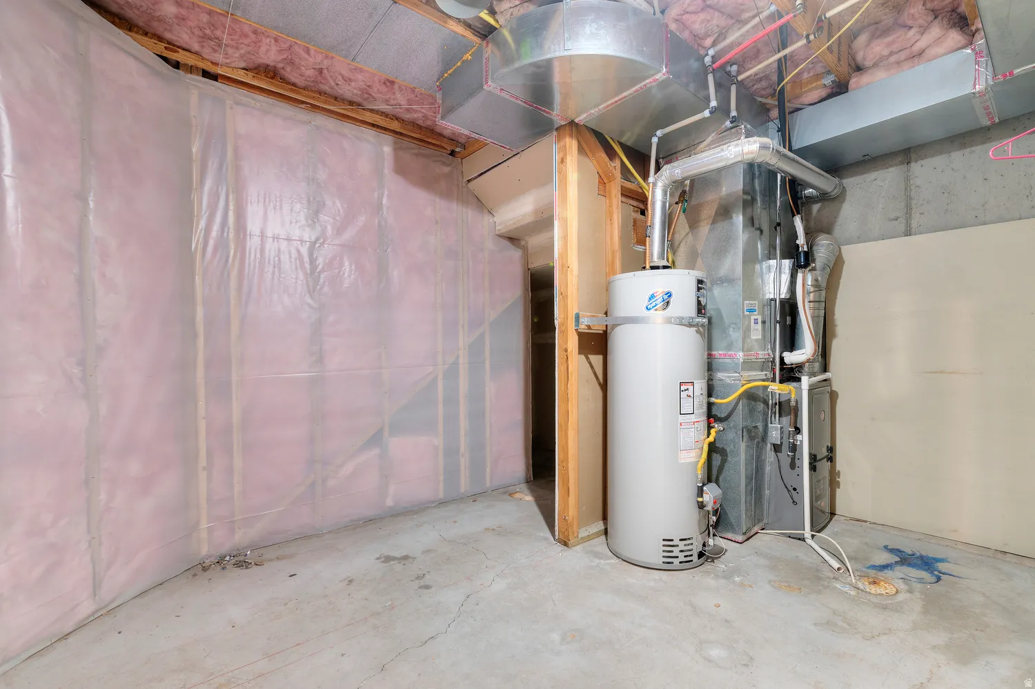 Unfinished basement space featuring a water heater, furnace, and exposed ductwork