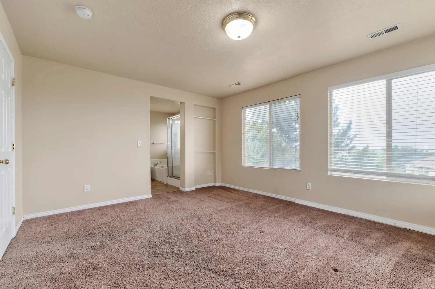 Spacious room featuring neutral-toned walls and plush carpeting