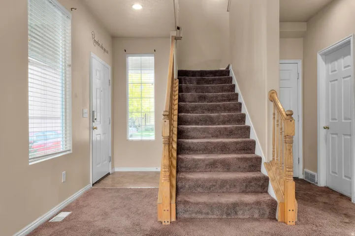 Entryway featuring carpeted flooring and a wood baluster staircase