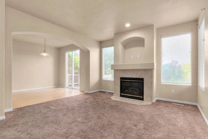 Living room featuring a corner fireplace with a tile surround and mantel, built-in niche, and large windows with blinds