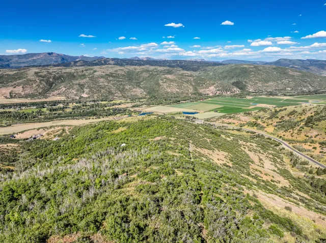 Expansive mountainous terrain featuring lush green foliage and agricultural fields